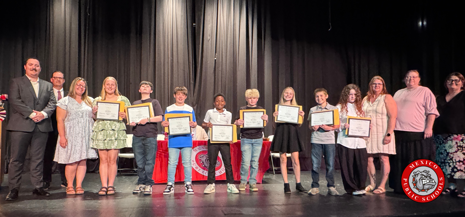 Group of students on stage, holding certificates